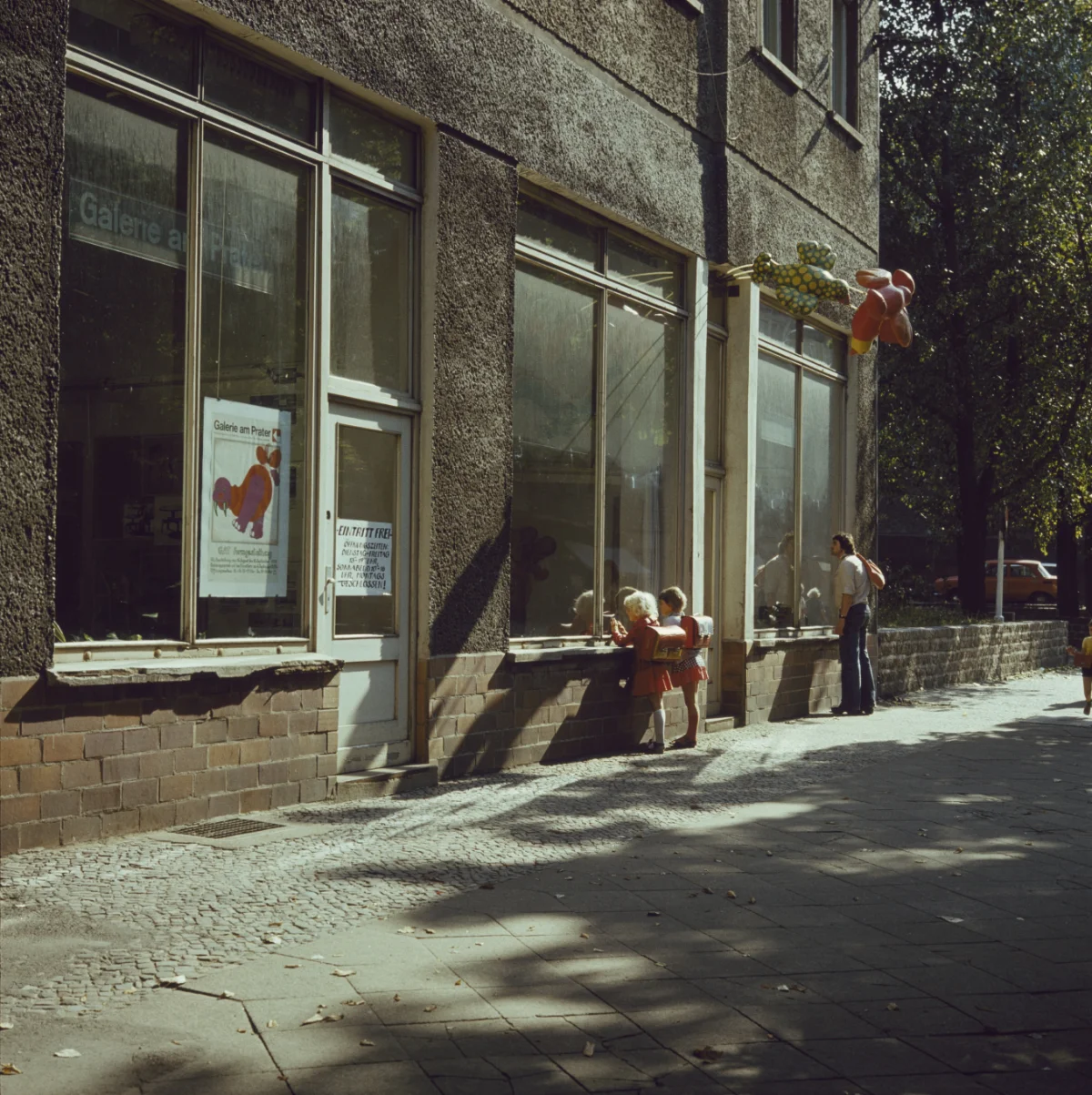 Zwei Kinder und ein Mann blicken durch die Schaufenster in den Galerieraum.